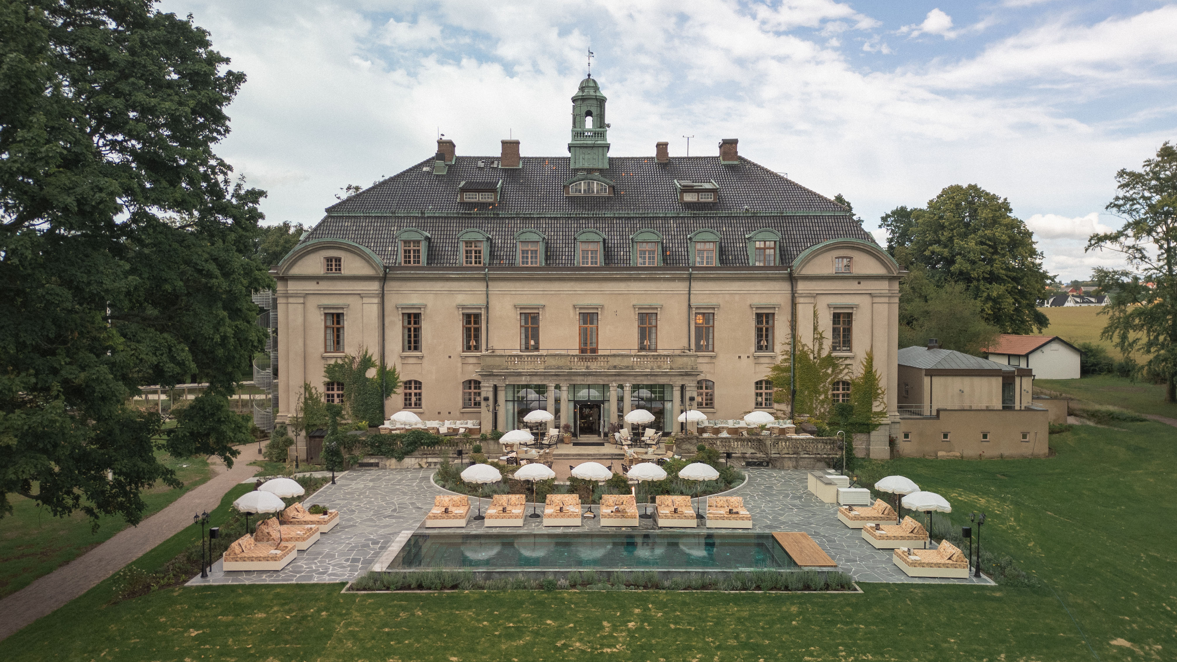 Fasaden av Maryhill Estate, ett barockslott från 1900-talet. Pool och loungeområde med trevliga solsängar